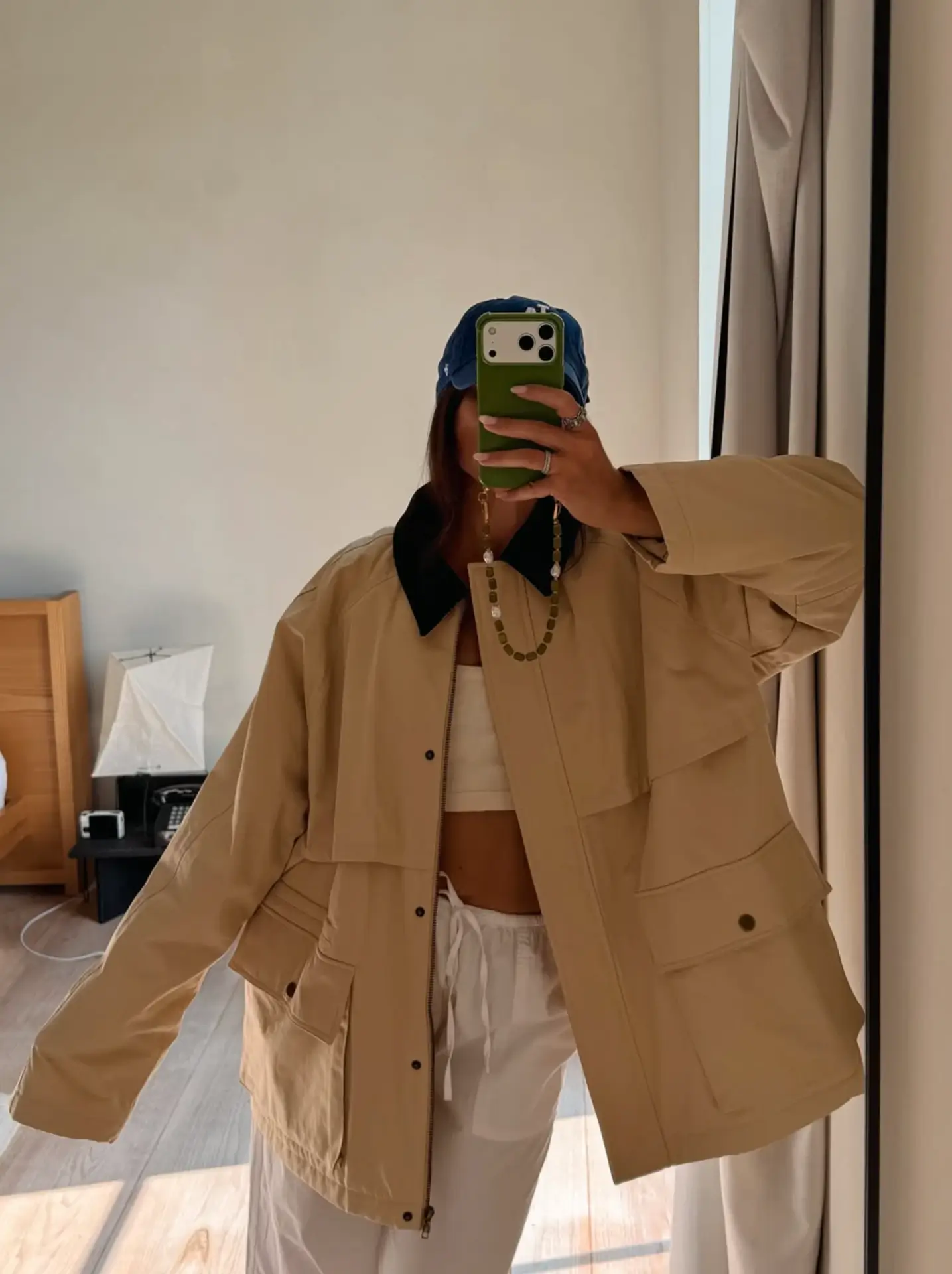 Creator taking a mirror selfie in a beige utility jacket