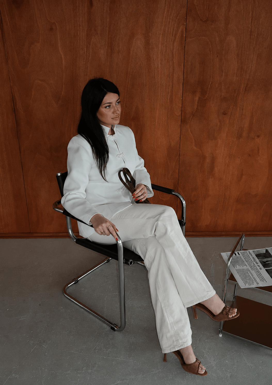 Creator in a white tailored suit seated against a wood-panelled wall