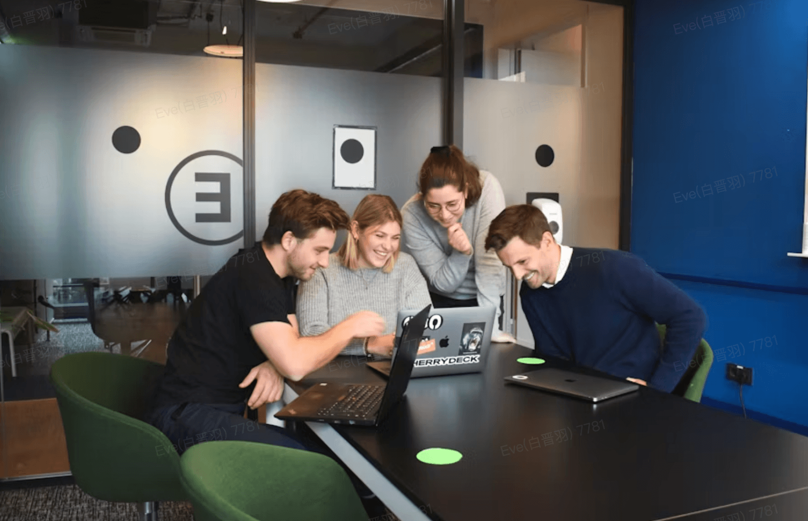 A team gathered around a laptop in a meeting room